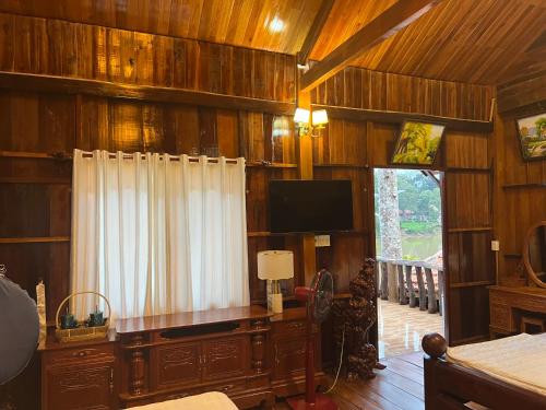 吉仙猫田河度假村的客厅设有木墙和平面电视。