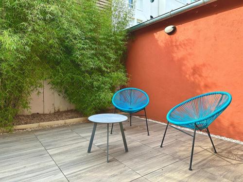 勒芒Le Patio de Loiseau的两把蓝色的椅子和一张桌子,旁边是一面墙