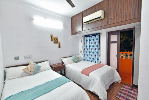 蓬蒂切里Coral Home Stay的一间卧室设有两张床、一台电视和一扇窗户。
