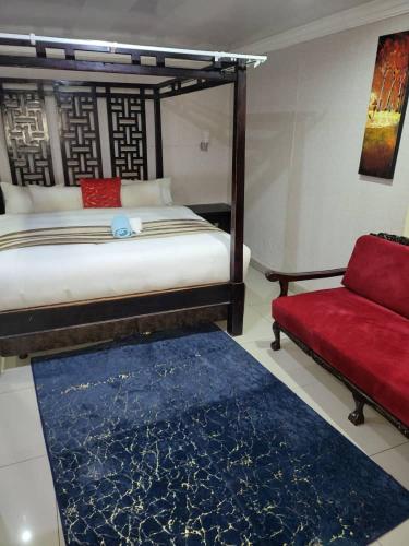 比勒陀利亚At Blackwood Guesthouse的一间卧室配有一张床和一张红色的沙发