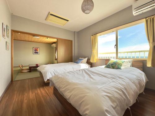 KannouraHotel NALU　ホテルナル的一间卧室设有两张床和大窗户