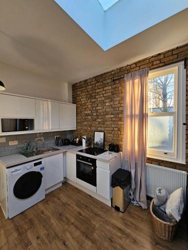 伦敦Putney Thames garden flat的厨房配有白色家电和窗户