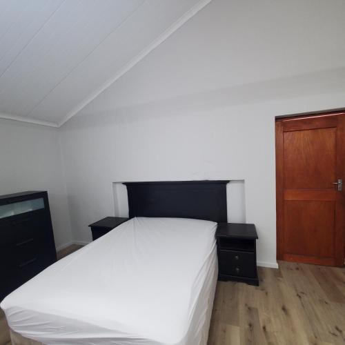 蒙塔古Kupenda Africa的卧室配有白色的床和木制橱柜。