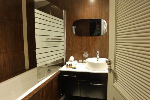 玛丽娜斯米尔PLAYA DEL PACHA Suites Hotel的一间带水槽、镜子和淋浴的浴室