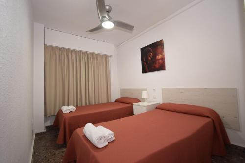 贝尼多姆Torre Principado II - Fincas Arena的酒店客房带两张带橙色床单的床
