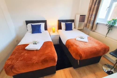 切尔滕纳姆Captivating 4-Bed House in Cheltenham的配有蓝色和橙色床单的客房内的两张床