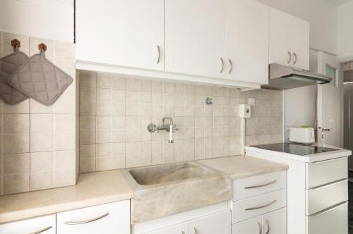 比雷埃夫斯Seafront Apartment in Piraeus的厨房配有水槽和白色橱柜