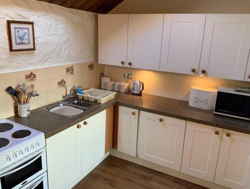 锡德茅斯Cider Cottage - 3 Bedroom - Onsite Parking的厨房配有白色橱柜、水槽和炉灶。
