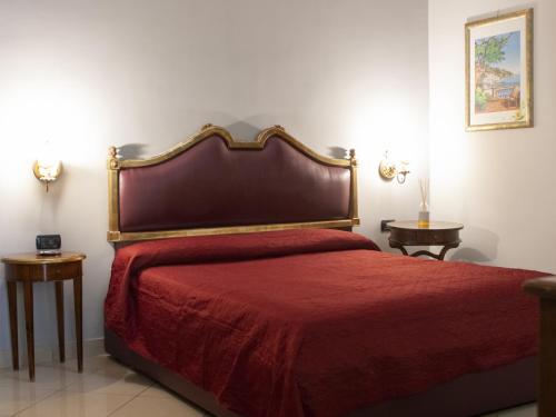 那不勒斯Hotel Serena的一间卧室配有一张带红色床罩的床和两张桌子