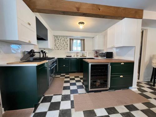 利奇菲尔德Litchfield Modern Farmhouse的厨房设有绿色橱柜和 ⁇ 格地板