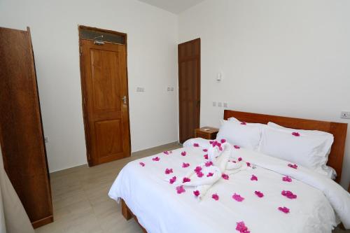 IMARA VILLA的卧室配有白色的床铺,上面有粉红色的鲜花