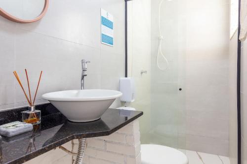 布希奥斯Centro Lindo Apt a 10 min da Rua das Pedras - Buzios Rentals的白色的浴室设有水槽和淋浴。