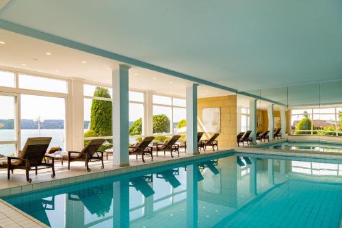 施坦贝尔格湖畔贝格莱尼赛酒店的大楼内带桌椅的大型游泳池