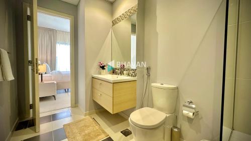 迪拜Calm Chaos 4 BR Villa with maid Room in Damac Hills 2的一间带卫生间、水槽和镜子的浴室