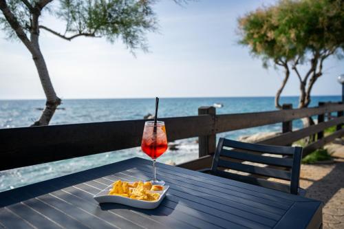 梵蒂冈角Villaggio Torre Ruffa的坐在海滩旁的桌子上喝一杯