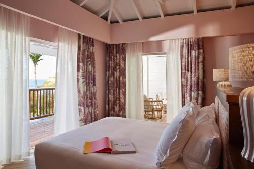 古斯塔维亚Tropical Hotel St Barth的一间卧室配有一张带书籍的床和一个阳台