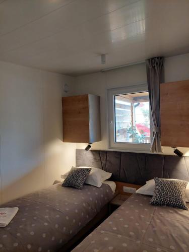 沃迪切Julija Mobile Lux的一间小卧室,配有两张床和窗户