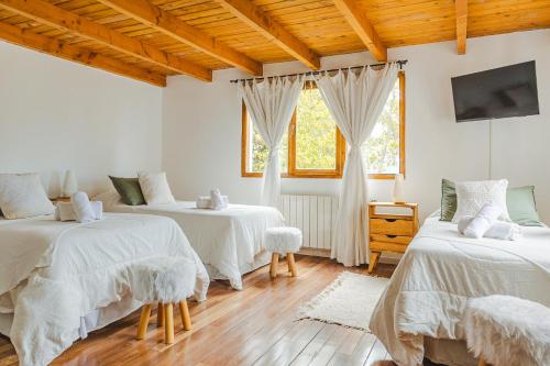 圣卡洛斯-德巴里洛切Hosteria Boutique Bariloche的一间卧室设有两张带白色床单的床和窗户。