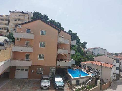 巴什卡沃达Apartments Vila Adrijana & Fitness Studio WOLF BV的2辆汽车停在带游泳池的大楼前