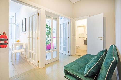 波尔图Alegria Colour Apartments的一间带绿色沙发的客厅和一间浴室