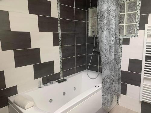 勒米尔蒙Appartement moderne的浴室铺有黑白瓷砖,配有白色浴缸。