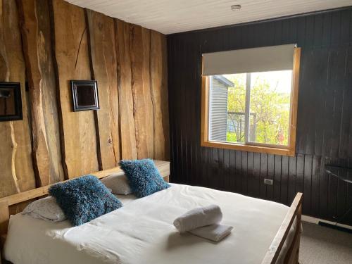 卡斯特鲁Hostal Plaza Chiloe的一间卧室配有一张带蓝色枕头的床和一扇窗户。