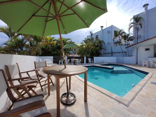 弗洛里亚诺波利斯Canas Gold Praia Hotel的一张桌子,旁边是一把绿色遮阳伞