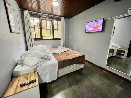 卡内拉Pousada Bella Serra的卧室配有一张床,墙上配有电视。