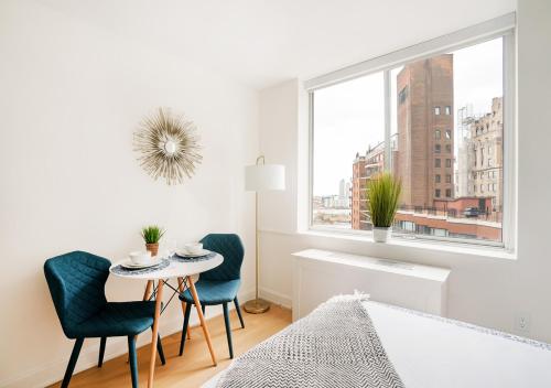 纽约Unique Studio Apartment At East Side的白色卧室配有桌椅和窗户