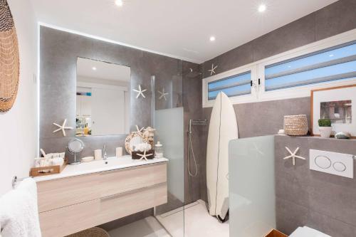 Anse des CayesArt et mer suite Saint barth的一间带水槽、镜子和冲浪板的浴室