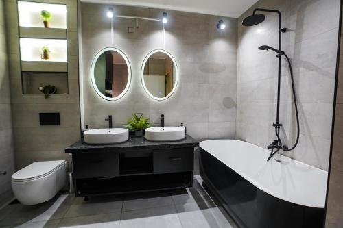 开罗Spacious flat 7 mins to Airport的浴室设有2个水槽、浴缸和镜子