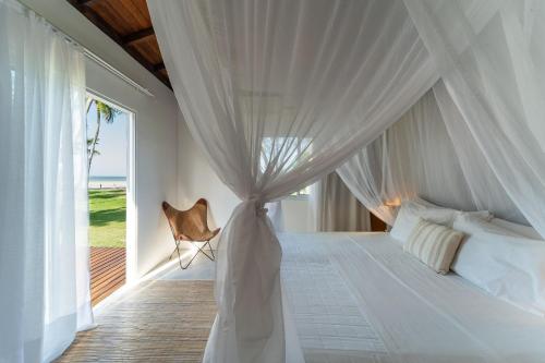 莫罗圣保罗Orixás Residence的卧室配有白色天蓬床和窗户