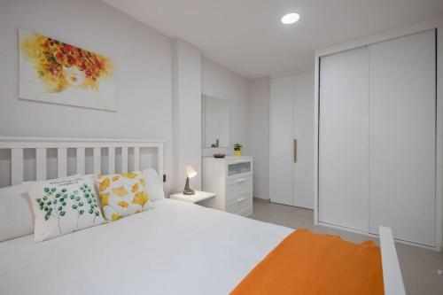 大加那利岛拉斯帕尔马斯Coqueto apartamento cerca playa的白色卧室配有白色的床和白色橱柜