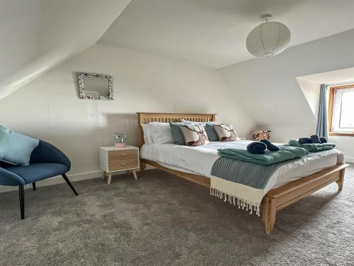 赫姆斯代尔Tigh Na Mara的一间卧室配有一张床和一张蓝色椅子