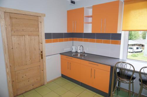 阿卢克斯内Holiday Apartment的厨房配有橙色橱柜、水槽和门
