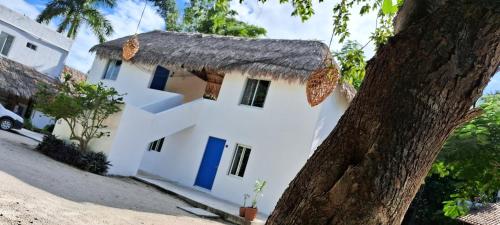 巴卡拉尔Posada Mykonos的白色的房子,有茅草屋顶和一棵树