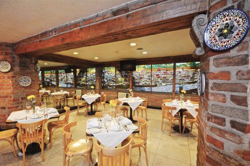 墨西哥城PF酒店的一间带桌椅的餐厅以及砖墙