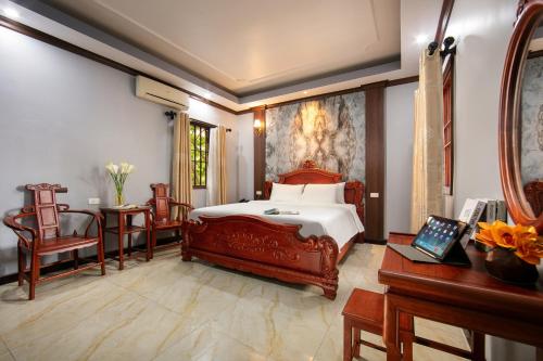 河内Nam Hai Hotel的卧室配有一张床和一张桌子及椅子