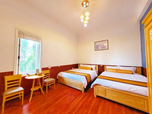 大叻Villa H Flower Đà Lạt的一间卧室配有两张床和一张桌子及椅子