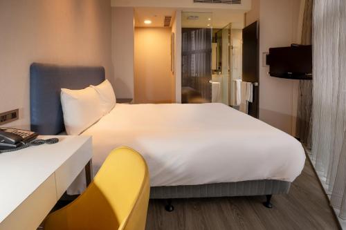 台北雀客旅馆台北信义的卧室配有一张白色大床和一张黄色椅子