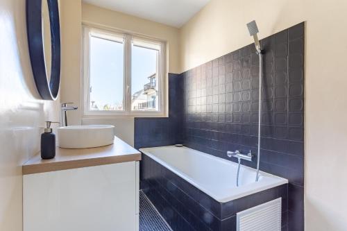 多维尔Le Carrousel - Appartement avec studio attenant的带浴缸、水槽和窗户的浴室