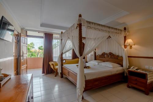 库塔峇里岛棕榈滩大酒店的一间卧室,卧室内配有一张天蓬床