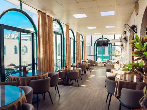 纳布卢斯Al Yasmeen Hotel的餐厅设有桌椅和窗户。