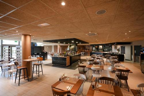 鲁瓦西昂法兰西坎帕内尔鲁瓦西酒店的一间带木桌椅的餐厅和一间酒吧