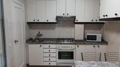 奥伦塞Enseñanza的厨房配有白色橱柜、炉灶和微波炉。