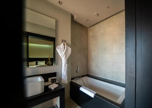 马拉喀什Hotel Le Rocher Marrakech的带浴缸、水槽和镜子的浴室
