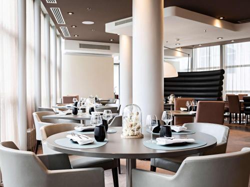 库尔布瓦铂尔曼巴黎德芬斯度假酒店的用餐室设有桌椅和窗户。