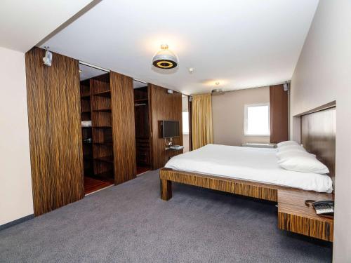 布拉格宜必思布拉格老城酒店的卧室配有一张白色大床和木制橱柜。
