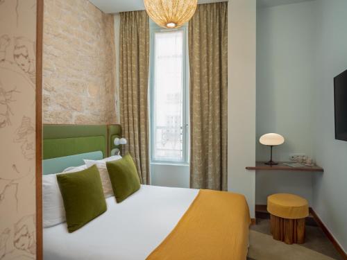 巴黎Hôtel Saint-André des Arts的一间卧室配有一张带绿色枕头的大床
