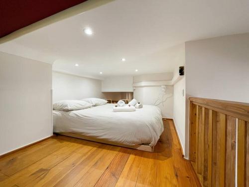 博索莱伊Le calmette的一间卧室配有一张铺有木地板的白色床单。